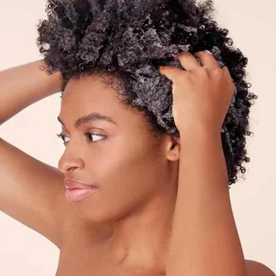 black woman applying conditioner to her hair